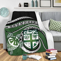 Green turtle blanket with shield emblem and geometric banding, laid across bed cover
