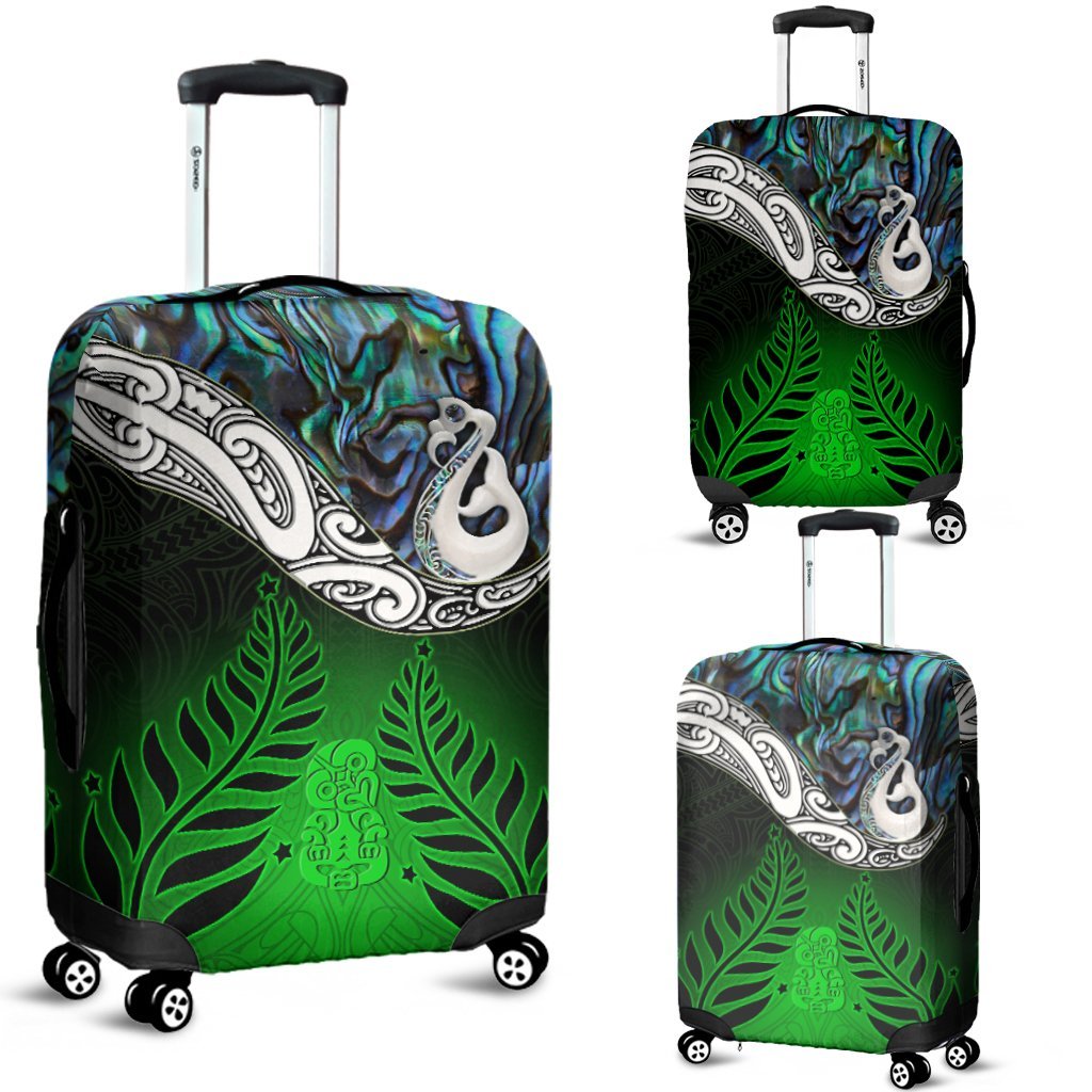 Green luggage cover with iridescent blue top, white manaia shell, and leaf pattern