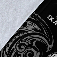 Close-up of black blanket with white tribal wave and geometric pattern, folded corner view