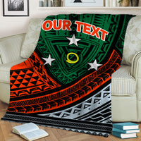 Personalized tribal blanket on couch, green/red/black geometric motifs with “YOUR TEXT”.