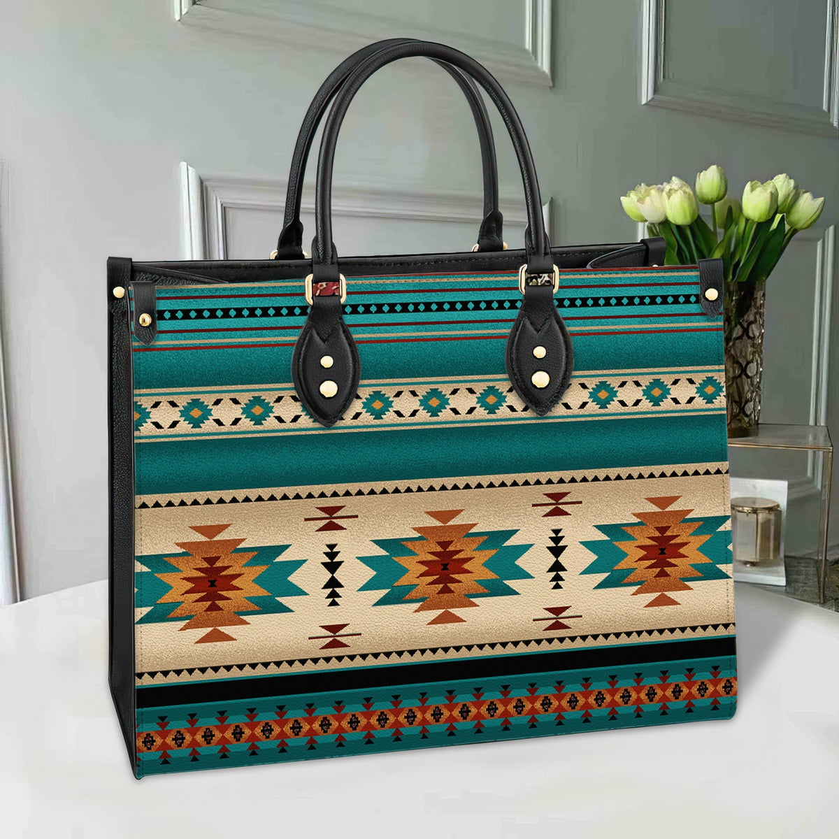 Native pattern leather bag in teal, black handles, gold studs, multicolor stripes
