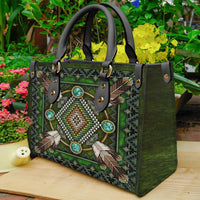 Green leather tote with beaded feather design, front snap pockets and black strap handles
