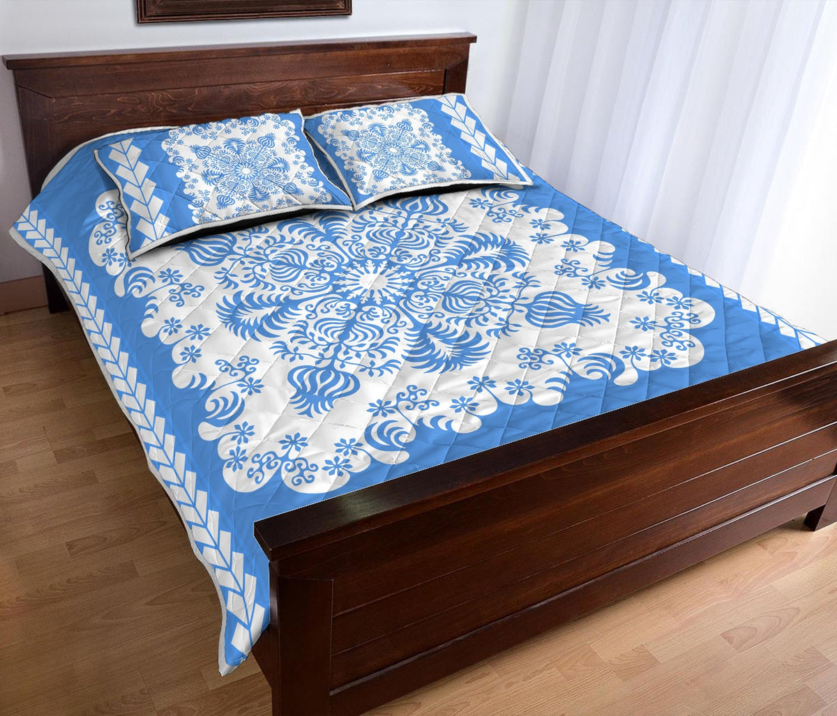 Folded corner view of blue quilt bed set with white swirls, flowers, and diagonal border