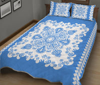 Blue quilt with white floral swirl pattern and geometric border; matching pillow shams