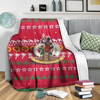 Red Christmas throw blanket with white patterned border, stars, and character emblem in center