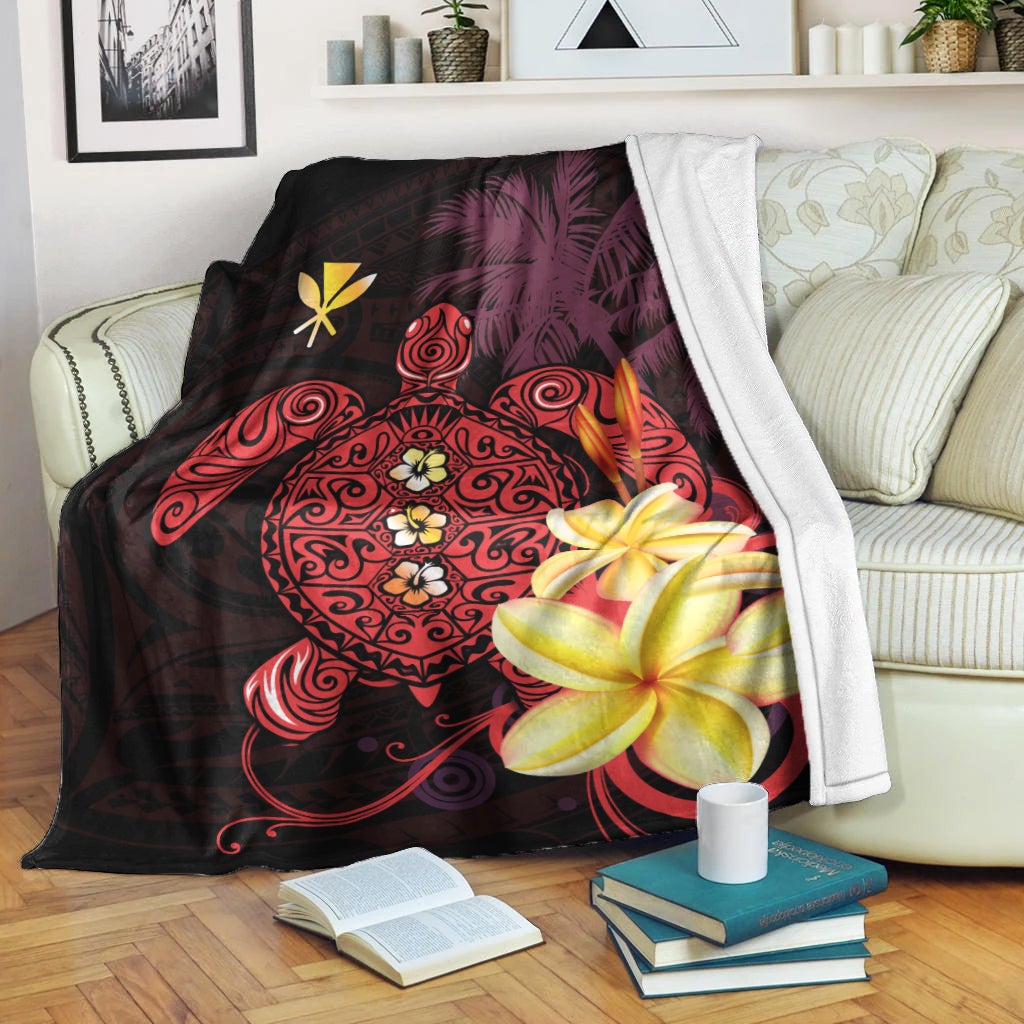 Hawaiian blanket draped on bed with turtle design and hibiscus flowers in red and yellow