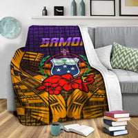 Samoa blanket folded on gray sofa, white backing edge, purple banner and red hibiscus