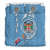 Blue bedding set studio view with two pillows; tapa pattern and Fiji crest emblem