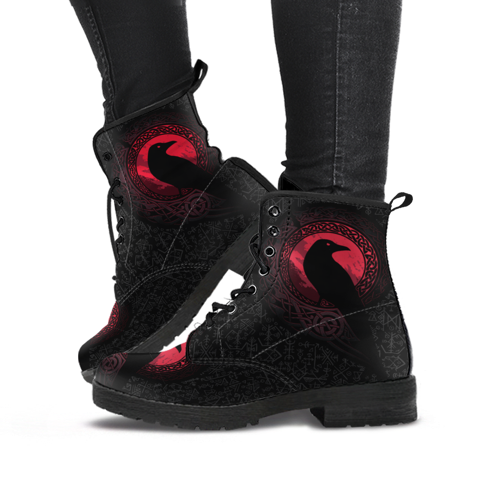 Black lace-up boots with red raven emblem, worn with dark pants