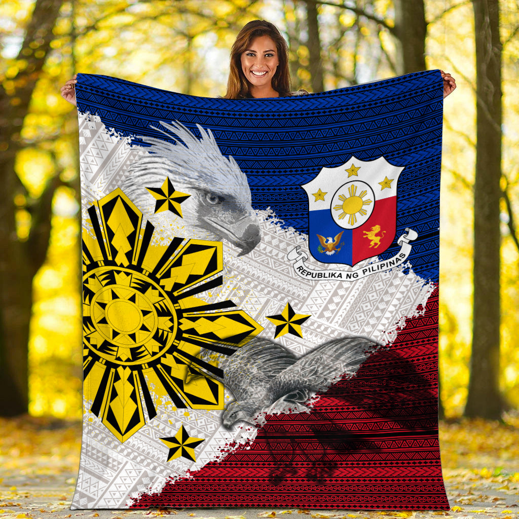 Philippines eagle blanket held up outdoors, blue top, red bottom, yellow sunburst emblem