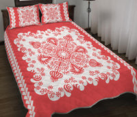 Red quilt with large white ornamental rosette motifs and diamond-edge trim; includes two shams