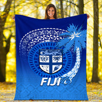 Blue Fiji tapa blanket laid out, shield crest with palm and wave motifs, “FIJI” text
