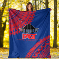 Blue throw blanket with red Samoan border pattern and FAST logo, outdoor view