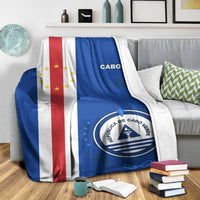 Cabo Verde blanket draped on sofa: blue panel, “CABO” text, round seal emblem
