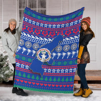Blue Christmas blanket spread out outdoors, featuring North Mariana Islands map and wreath badge