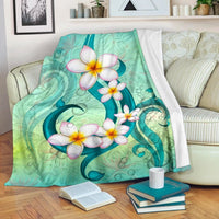Hawaii plumeria print blanket, teal-and-green with white flowers and dark teal vines.