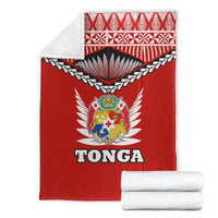 Red Tonga blanket with crest and TONGA text, folded white towels beside it