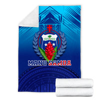 Blue Manu Samoa blanket with shield crest; folded with two rolled white towels