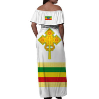White off-shoulder long dress with ruffled back, Ethiopian cross graphic and red-green hem stripe