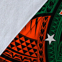 Close-up of blanket fabric: textured white backing with green/red/black tribal print.