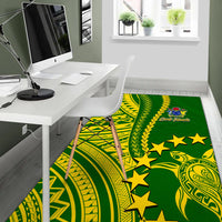 Green rug with yellow Polynesian patterns, stars, and crest near the center