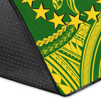 Corner close-up of green rug with yellow star and tribal pattern, black border