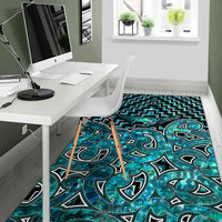 Turquoise and teal decorative area rug featuring swirl motifs with zigzag trim border