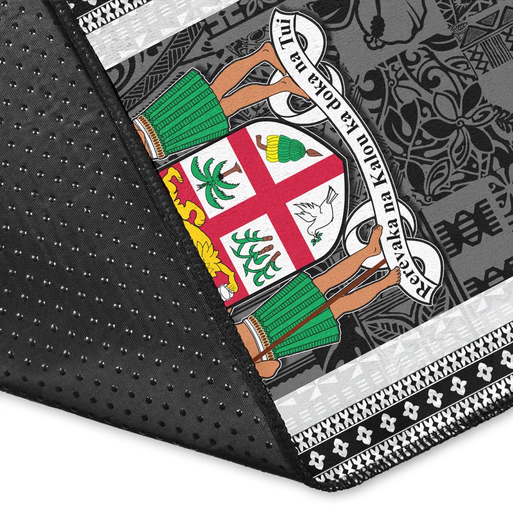 Fiji area rug corner close-up, dark fabric with white patterned trim and colorful crest