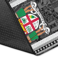 Fiji area rug corner close-up, dark fabric with white patterned trim and colorful crest