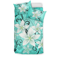 Turquoise comforter and pillowcases with white plumeria blooms and black swirling vines