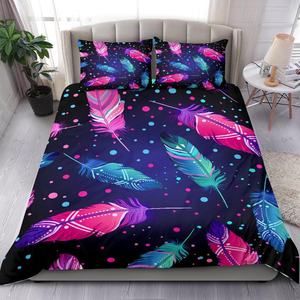 Feather-print comforter and two pillowcases in pink, blue, and teal on dark background
