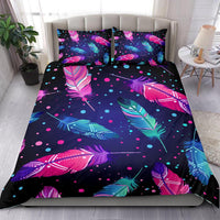 Feather-print comforter and two pillowcases in pink, blue, and teal on dark background