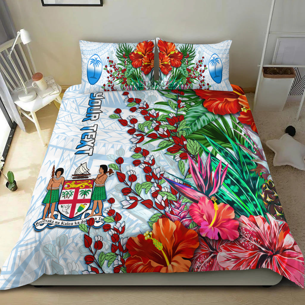 White Fiji bedding set with blue oval tapa motifs, red flowers, and green foliage