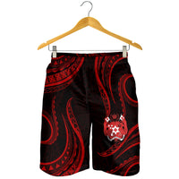 Men's Tonga pattern shorts hanging, dark with red tribal print and crest badge