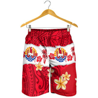 Red and white Polynesian print men's shorts hanging on a hanger, elastic waistband