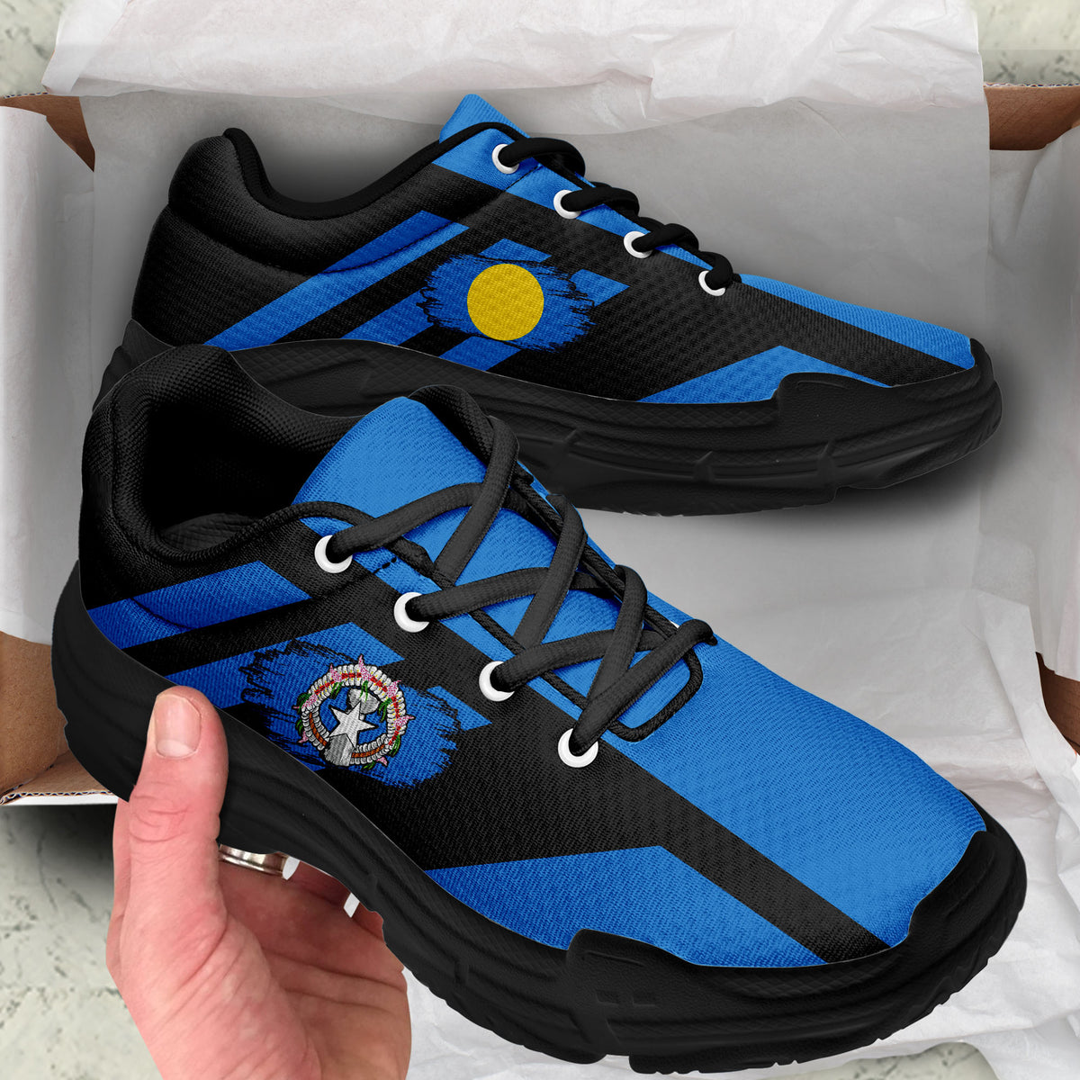 Black and blue chunky lace-up sneakers with yellow dot and crest patch; thick black sole