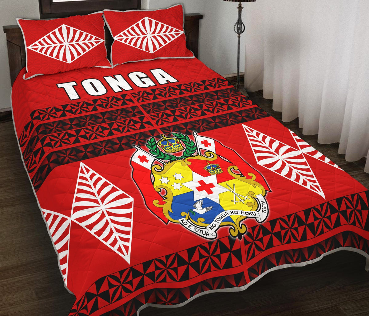 Red bed set with Tonga text across quilt, black geometric triangles, and white leaf shell pillows