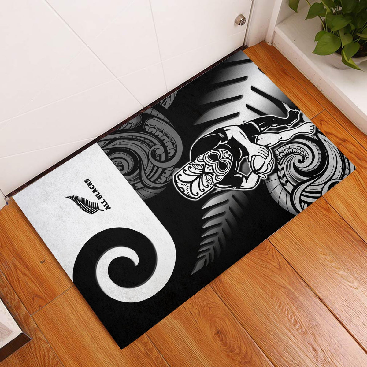 Black door mat with white Maori-style koru and tribal tiki design