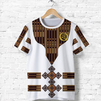 White t-shirt with bold Ethiopian-style pattern and central emblem graphic