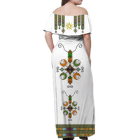 White off-shoulder long dress, back view, with central cross and floral motifs