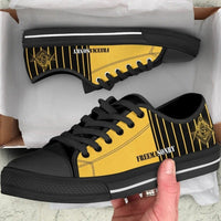 Side view of yellow/black low-top shoes with gold emblem and striped detail