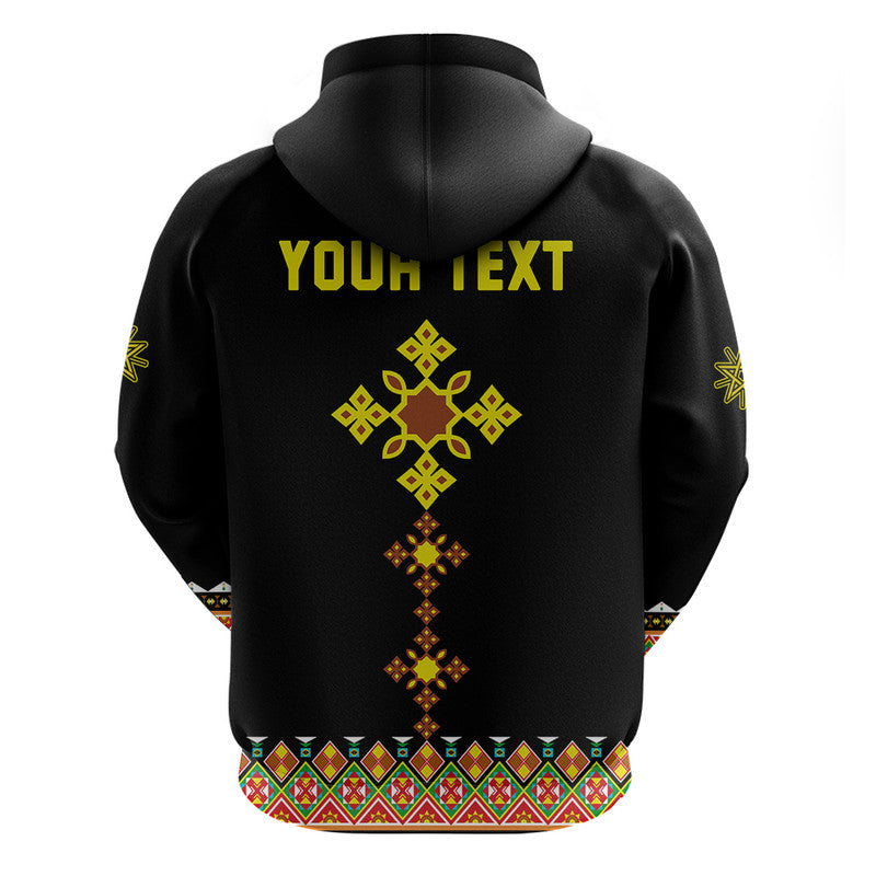 Black hoodie back with yellow cross design, 'YOUR TEXT' print, patterned hem