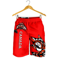 Red men’s shorts on hanger, Haida graphic with CANADA text, elastic waistband