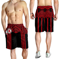 Model wearing black swim shorts with red geometric stripes and crest logo