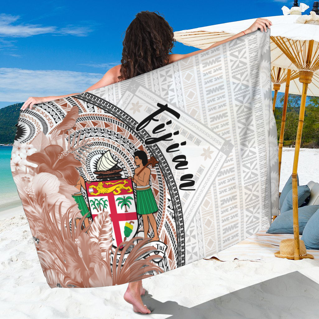 White tapa-print sarong with central figure, multicolor shield, and black script