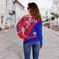 Off-shoulder sweater back view: red/blue with HAITI lettering and map emblem