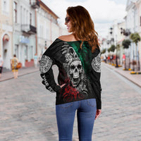 Black off-shoulder sweater with large skull graphic and green-red details, long sleeves