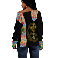 Black off-shoulder sweater back view with colorful geometric paneling and gold emblem