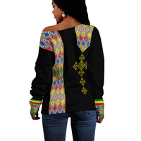 Black off-shoulder sweater, back view with multicolor geometric panel and emblem print