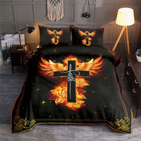 Full bedding set on bed: dark duvet with glowing cross, phoenix wings, roses, and border